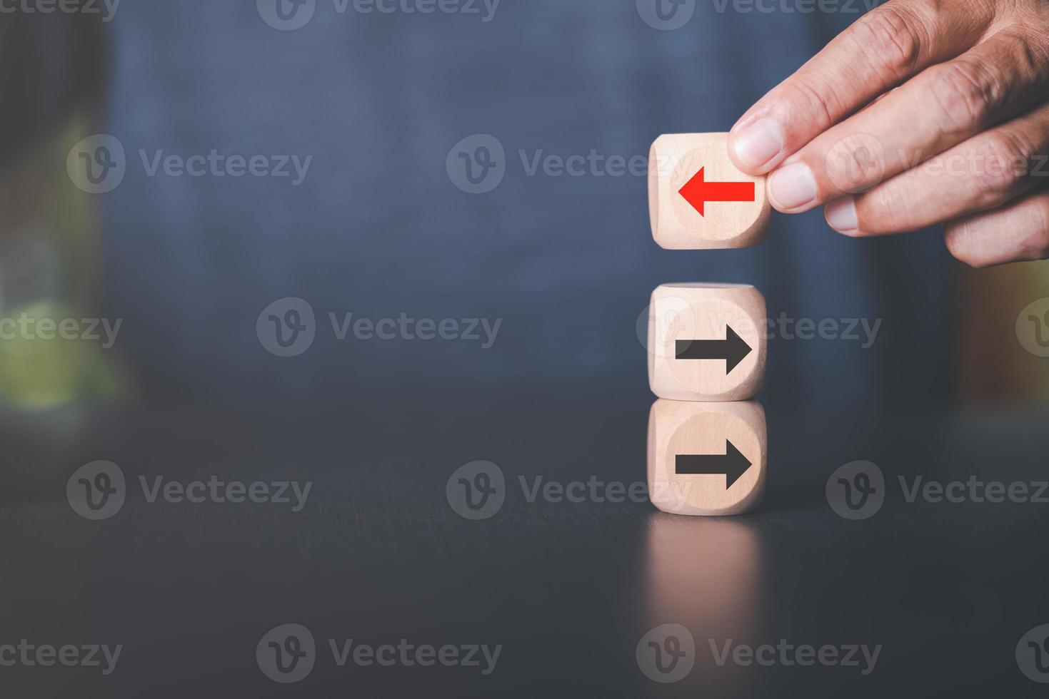 Young businessman selecting wooden blocks with red arrows and different directions Leadership concept and growth of business competition Changing Strategic Vision for Chances of Success photo