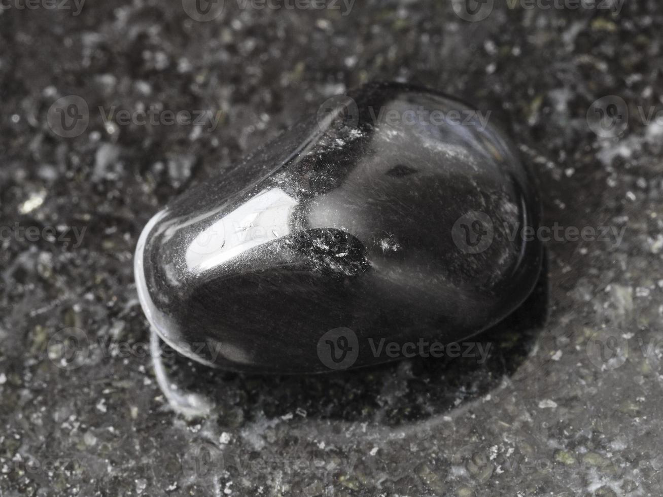 polished black obsidian gem stone on dark photo
