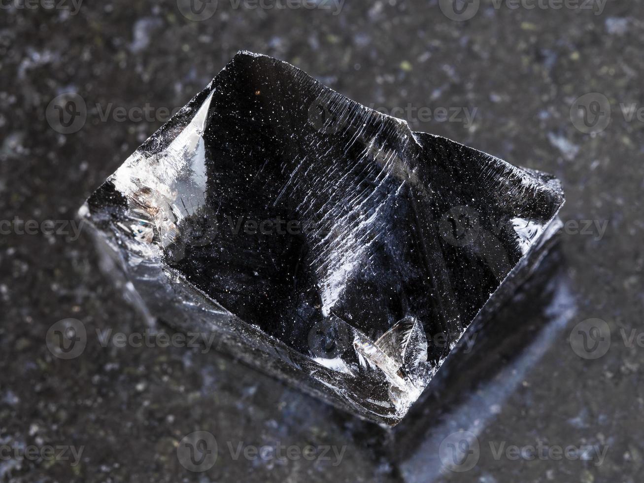 piece of rough Obsidian volcanic glass on dark photo