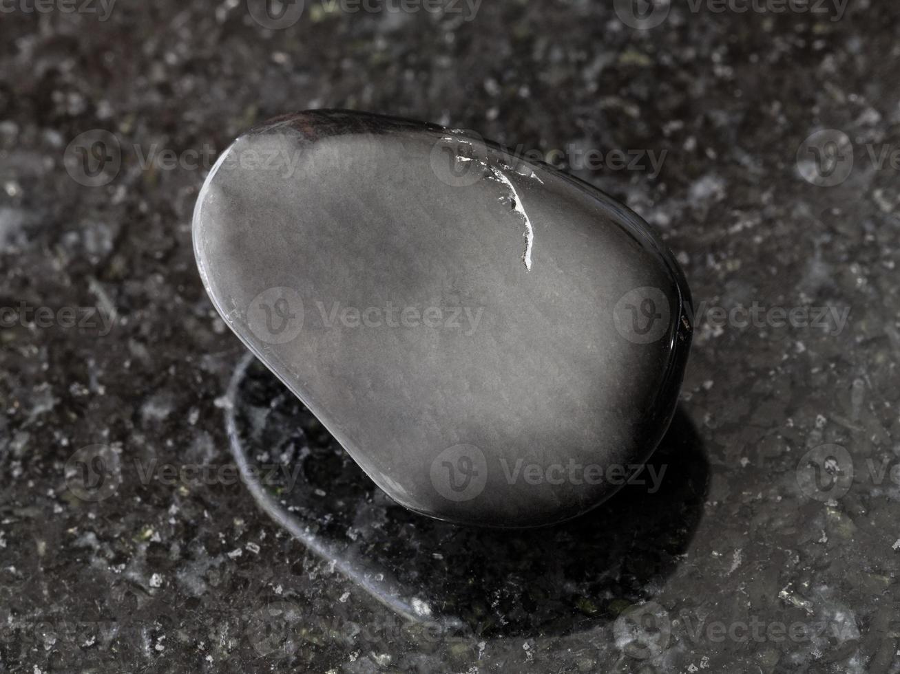 tumbled black obsidian gem stone on dark photo