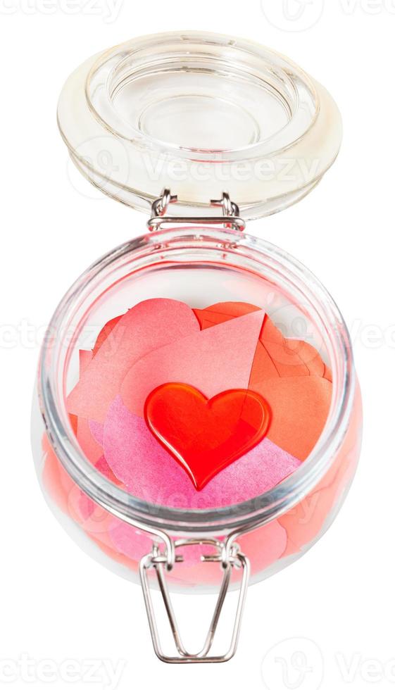 glass heart on pile of paper hearts in open jar photo
