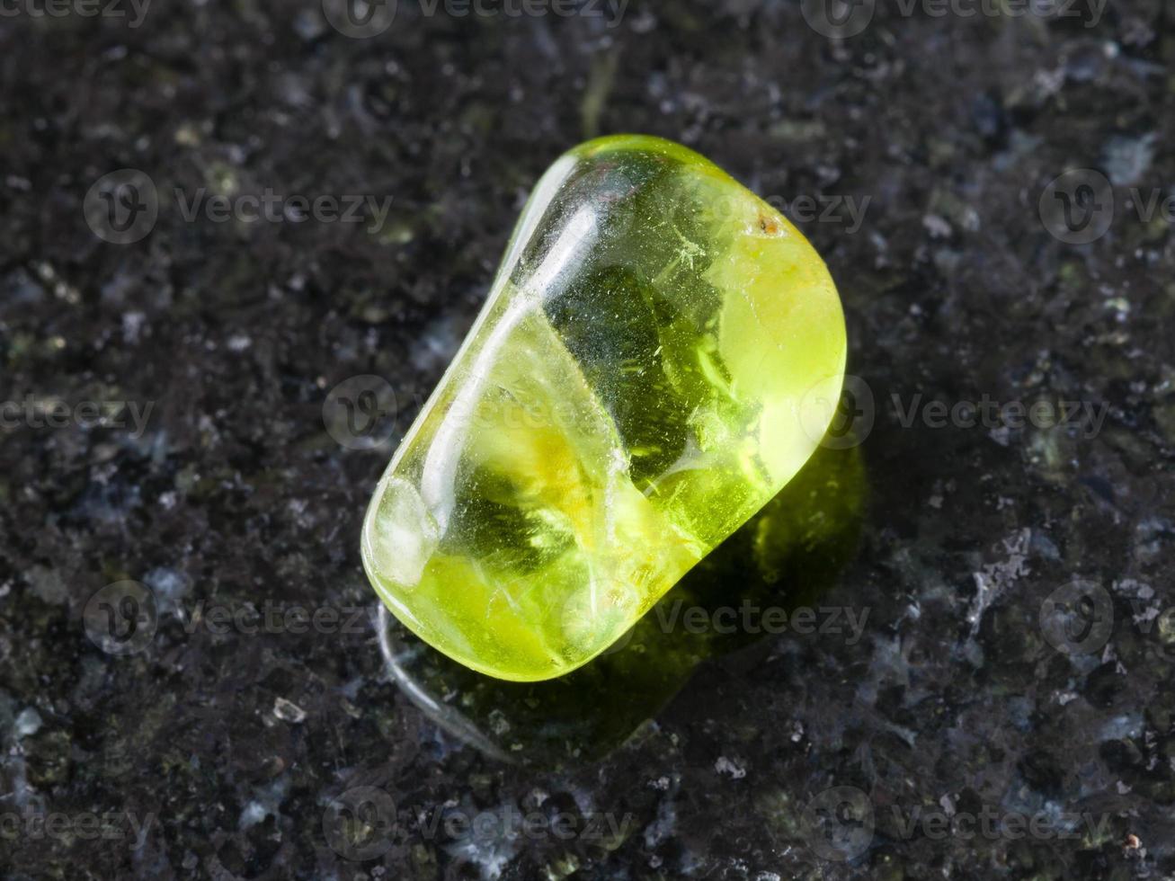 tumbled Peridot gem stone on dark background photo