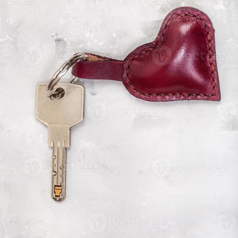 key with leather heart shape trinket on concrete photo