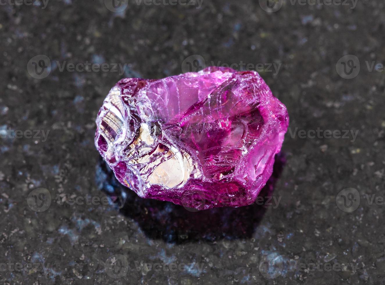 unpolished Rhodolite pyrope crystal on black photo