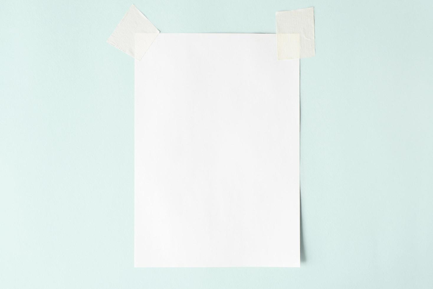 White sheet on scotch tape, layout. Blank sheet of paper on a pastel blue background, copy space photo