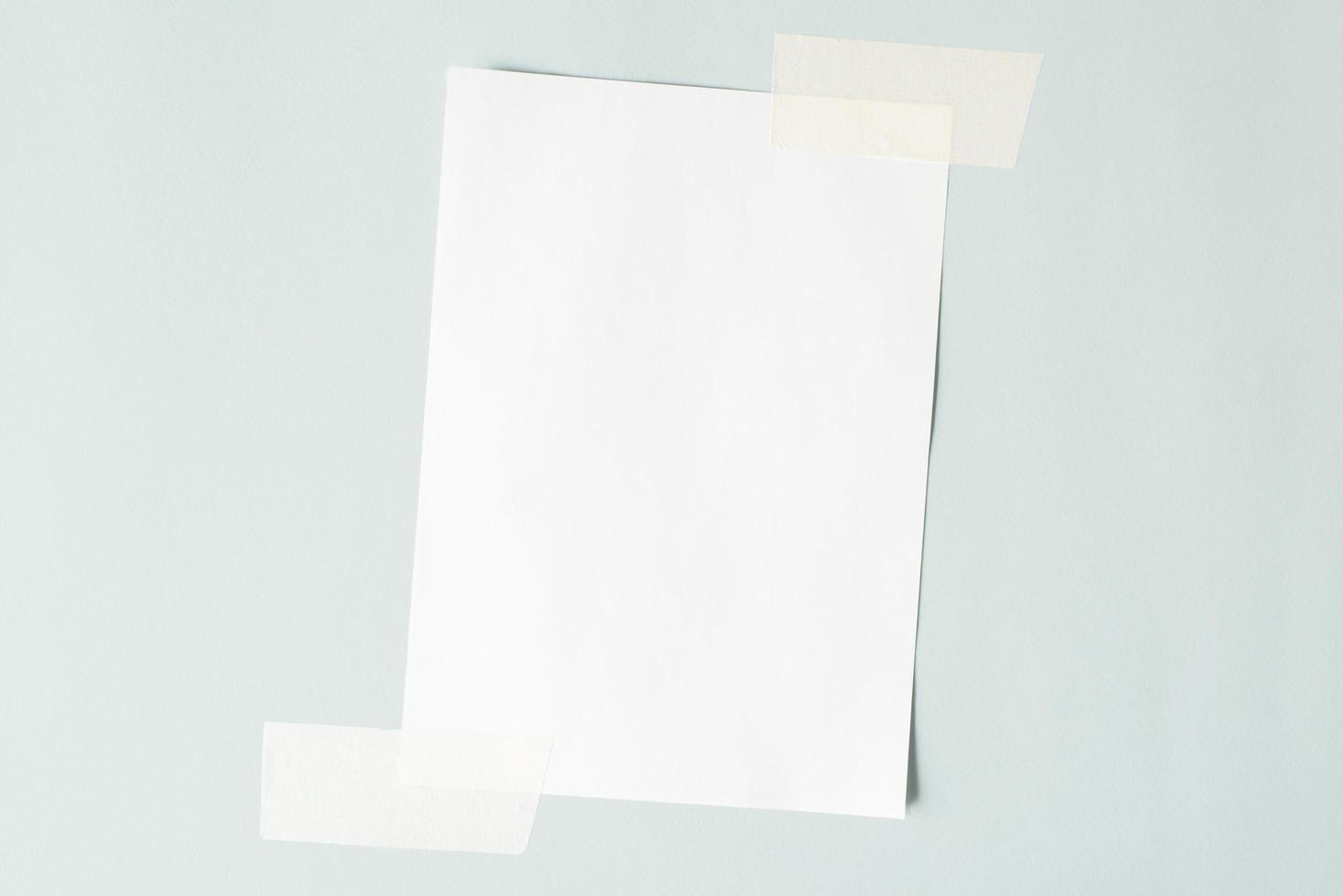 One sheet of paper crookedly pasted on the wall. White sheet mock up, copy space. photo