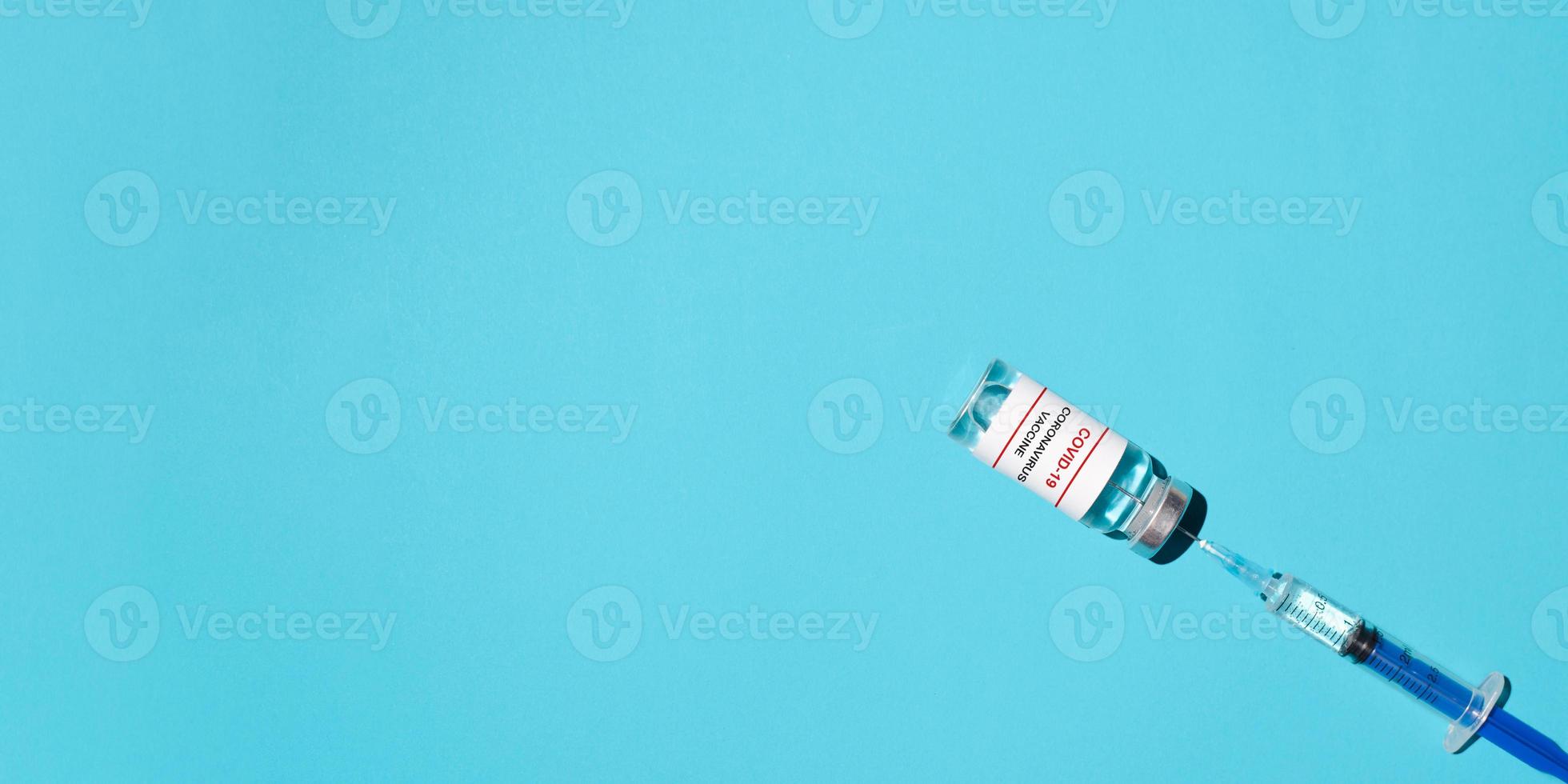 Syringe and vaccine covid-19 on a blue background, flat lay. Medical banner, copy space. Vaccination concept, injection photo