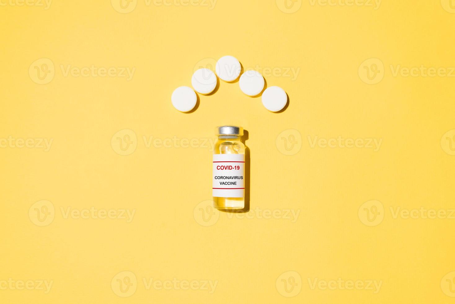 Vial of covid-19 vaccine and tablets in the shape of roof house on yellow background, flat lay. Virus protection concept photo