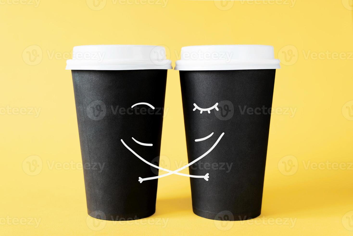 Loving couple of coffee cups. Hugging disposable coffee cups on a yellow background. Creative concept of romantic relationships photo