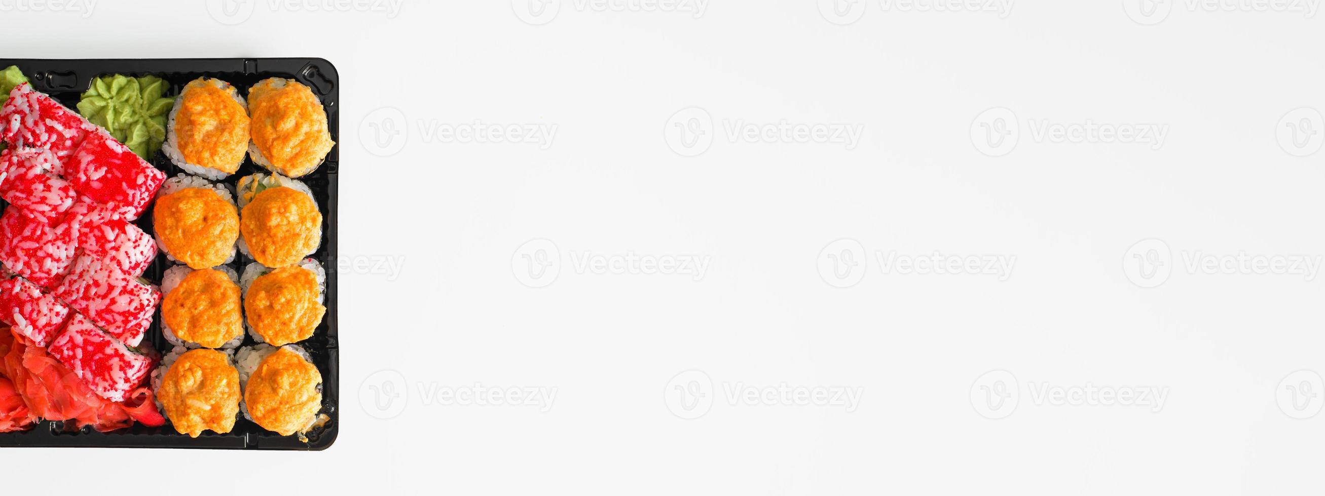 Set of baked and california rolls in plastic container on a white plate. Traditional Japanese food banner, copy space photo