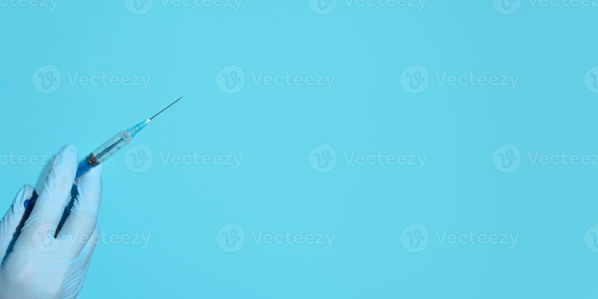 Vaccination concept. Doctor's hand in medical gloves holding a syringe injection. Banner, copy space, top view photo