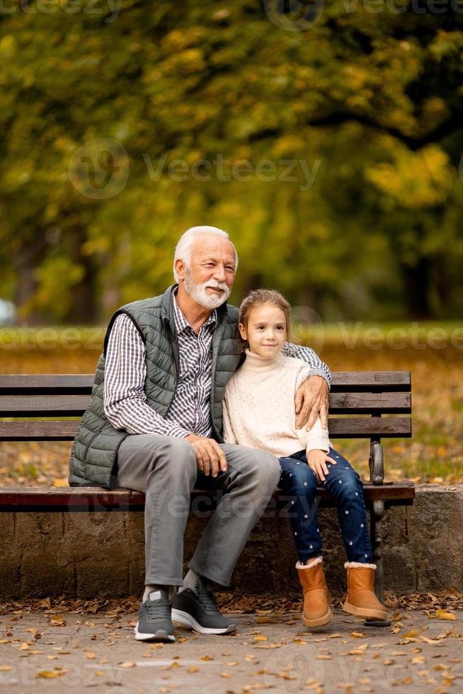 abuelo pasando tiempo con su nieta en un banco en el parque el día de otoño foto