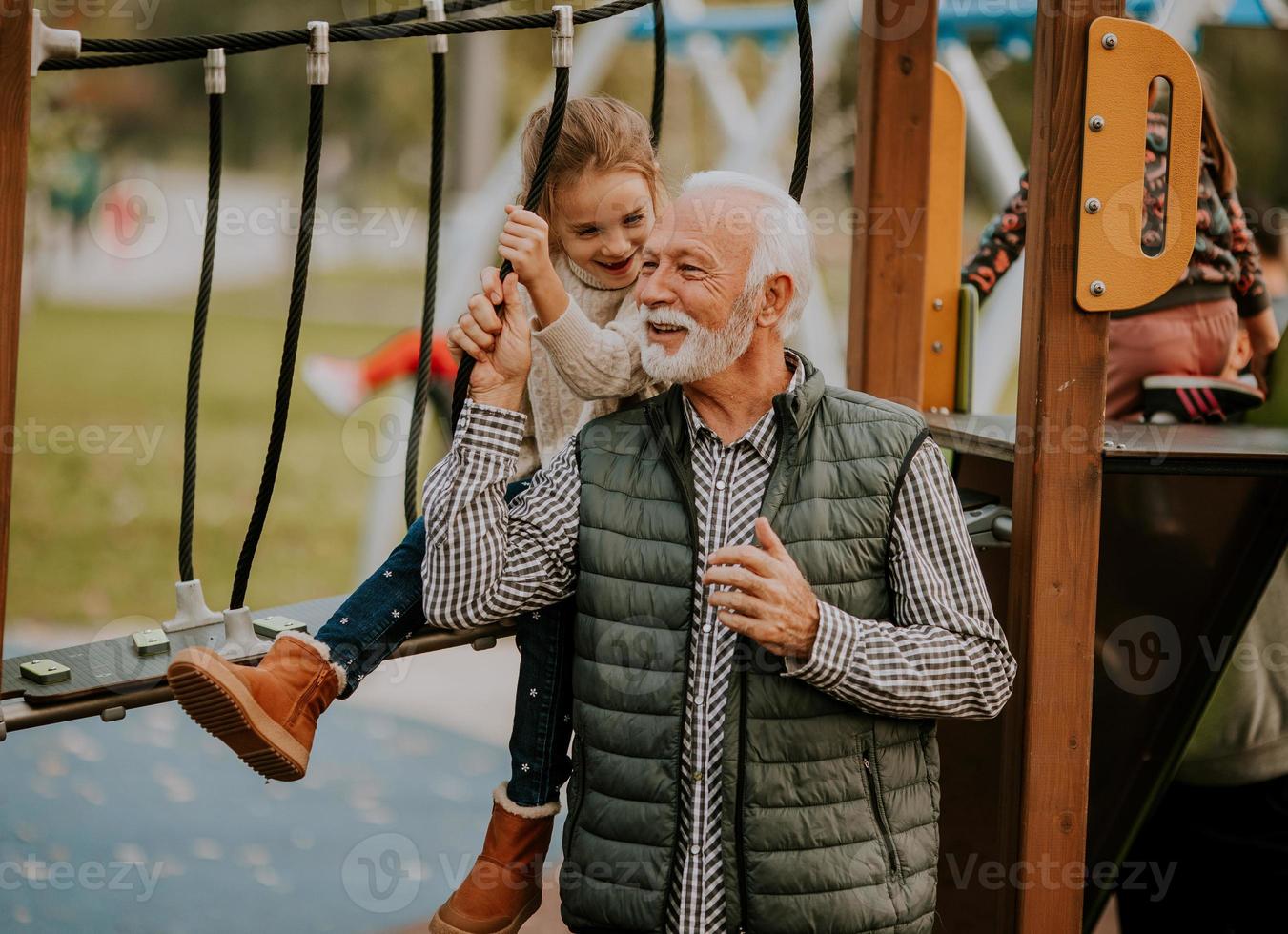 el abuelo pasa tiempo con su nieta en el parque infantil el día de otoño foto