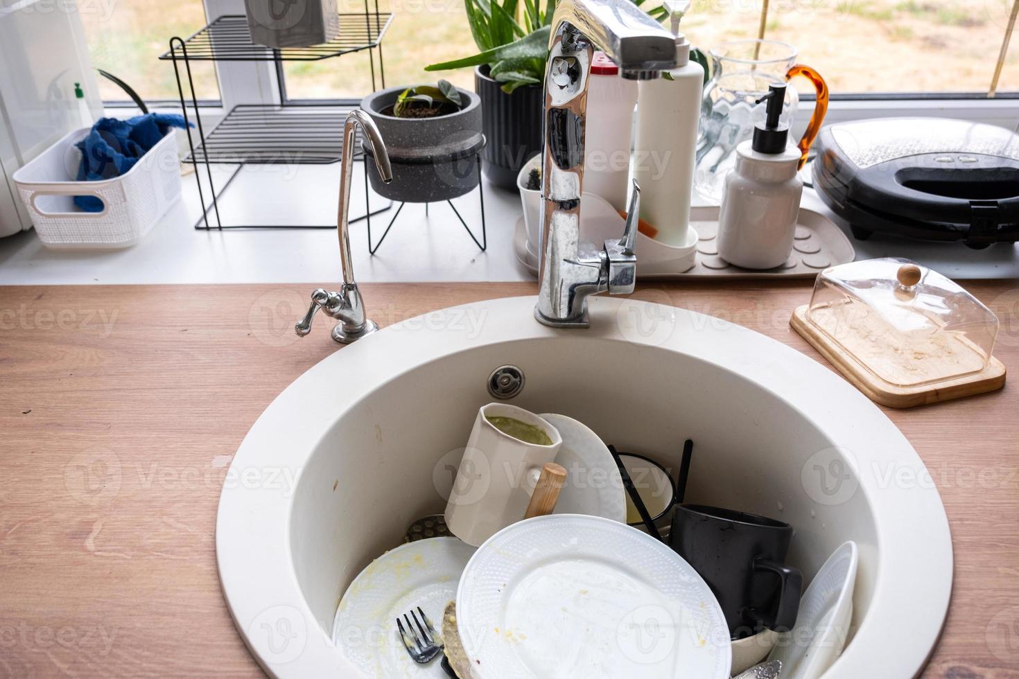 Dirty dishes in the sink in the kitchen, mess after lunch, too lazy to wash dishes. Kitchen cleaning, detergent, cleaning services photo