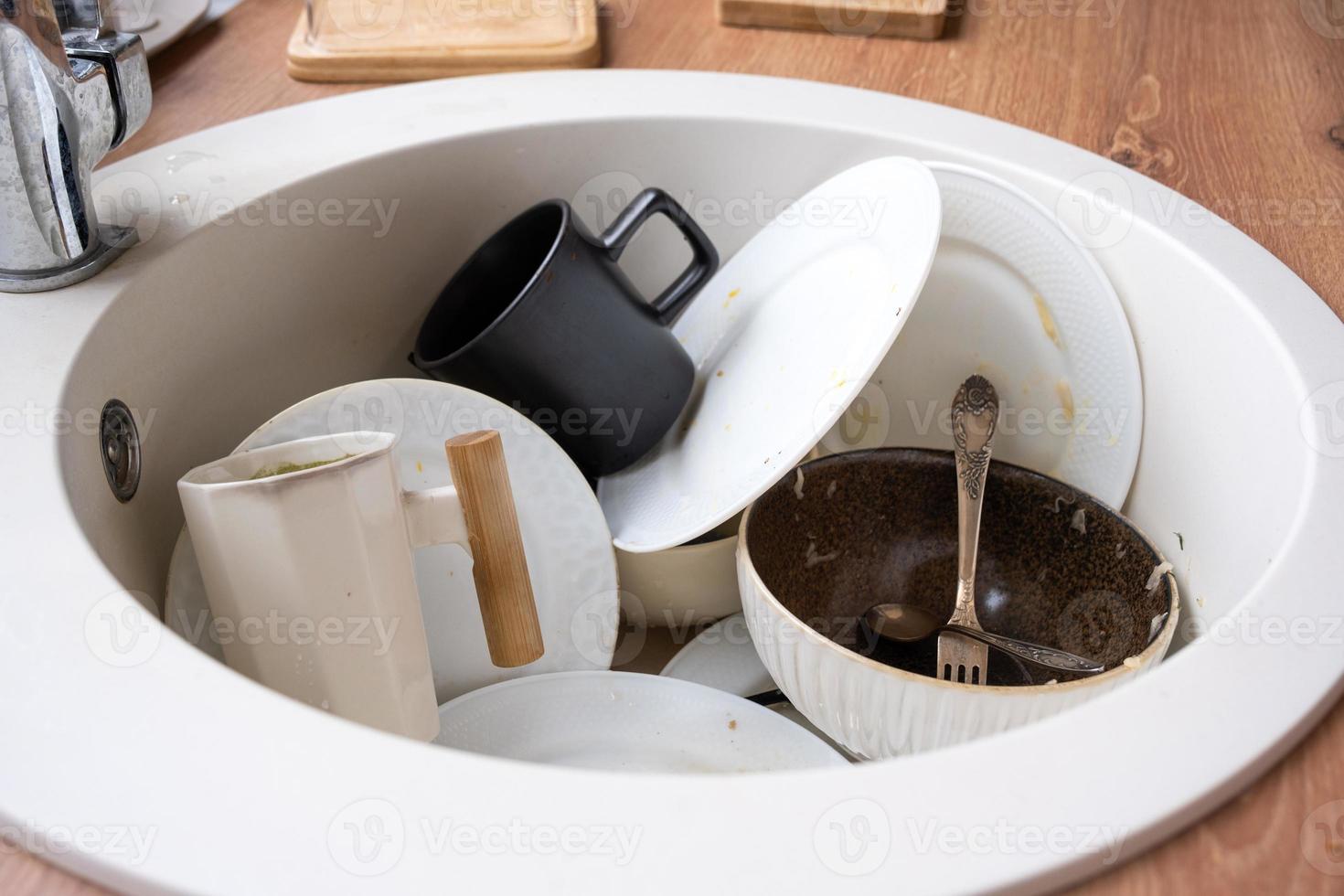 Dirty dishes in the sink in the kitchen, mess after lunch, too lazy to wash dishes. Kitchen cleaning, detergent, cleaning services photo