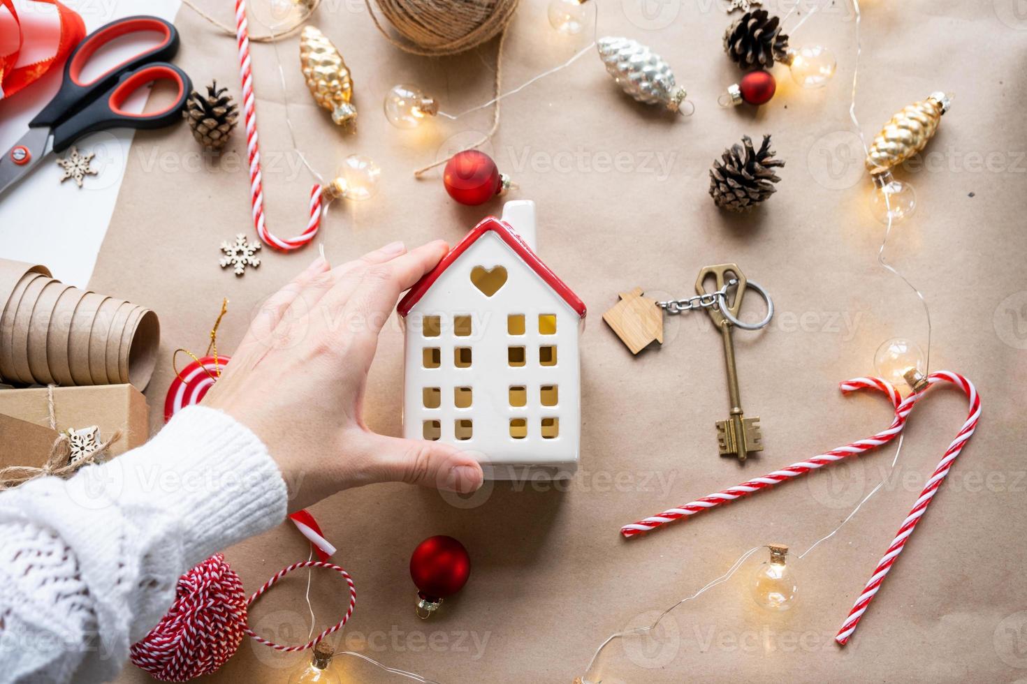 llave de la casa con un llavero en una casa acogedora con un diseño de decoración navideña. un regalo para año nuevo, navidad. construcción, diseño, proyecto, mudanza a casa nueva, hipoteca, alquiler y compra de bienes raíces foto