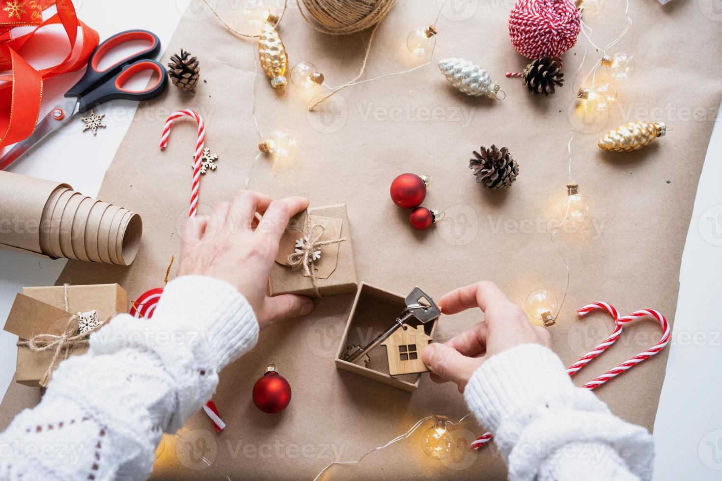 llave de casa con llavero en casa acogedora en caja de regalo con embalaje de decoración navideña. paquete de regalo para año nuevo, navidad. edificio, proyecto, mudanza a casa nueva, hipoteca, alquiler, compra de bienes raíces foto