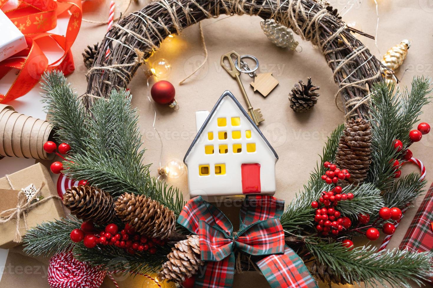 Key to the house with a keychain on a cozy home with a Christmas decor layout. A gift for New Year, Christmas. Building, design, project, moving to new house, mortgage, rent and purchase real estate photo