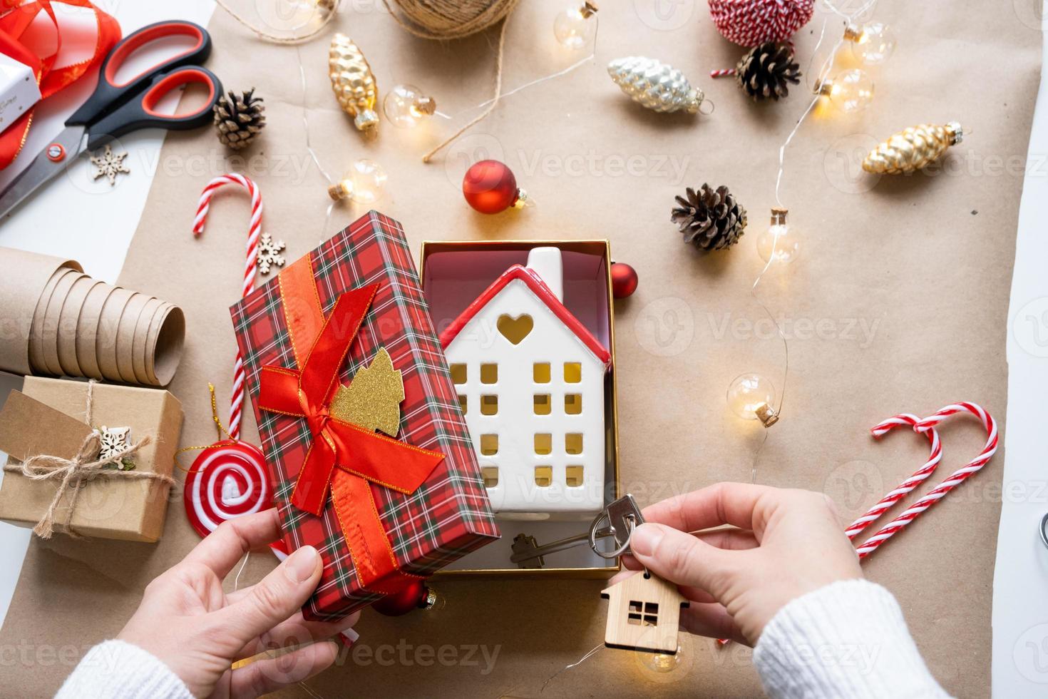 Key to house with keychain on cozy home in gift box with Christmas decor packaging. Pack present for New Year, Christmas. Building, project, moving to new house, mortgage, rent, purchase real estate photo