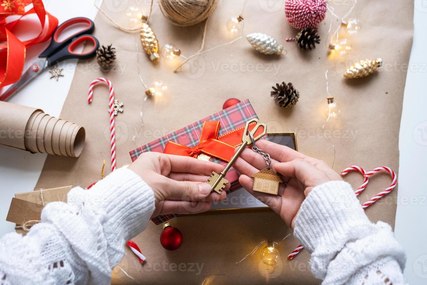 llave de casa con llavero en casa acogedora en caja de regalo con embalaje de decoración navideña. paquete de regalo para año nuevo, navidad. edificio, proyecto, mudanza a casa nueva, hipoteca, alquiler, compra de bienes raíces foto
