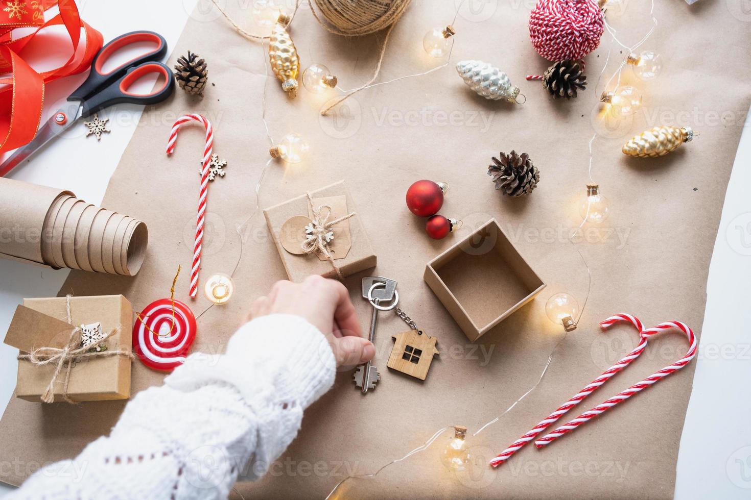 llave de casa con llavero en casa acogedora en caja de regalo con embalaje de decoración navideña. paquete de regalo para año nuevo, navidad. edificio, proyecto, mudanza a casa nueva, hipoteca, alquiler, compra de bienes raíces foto