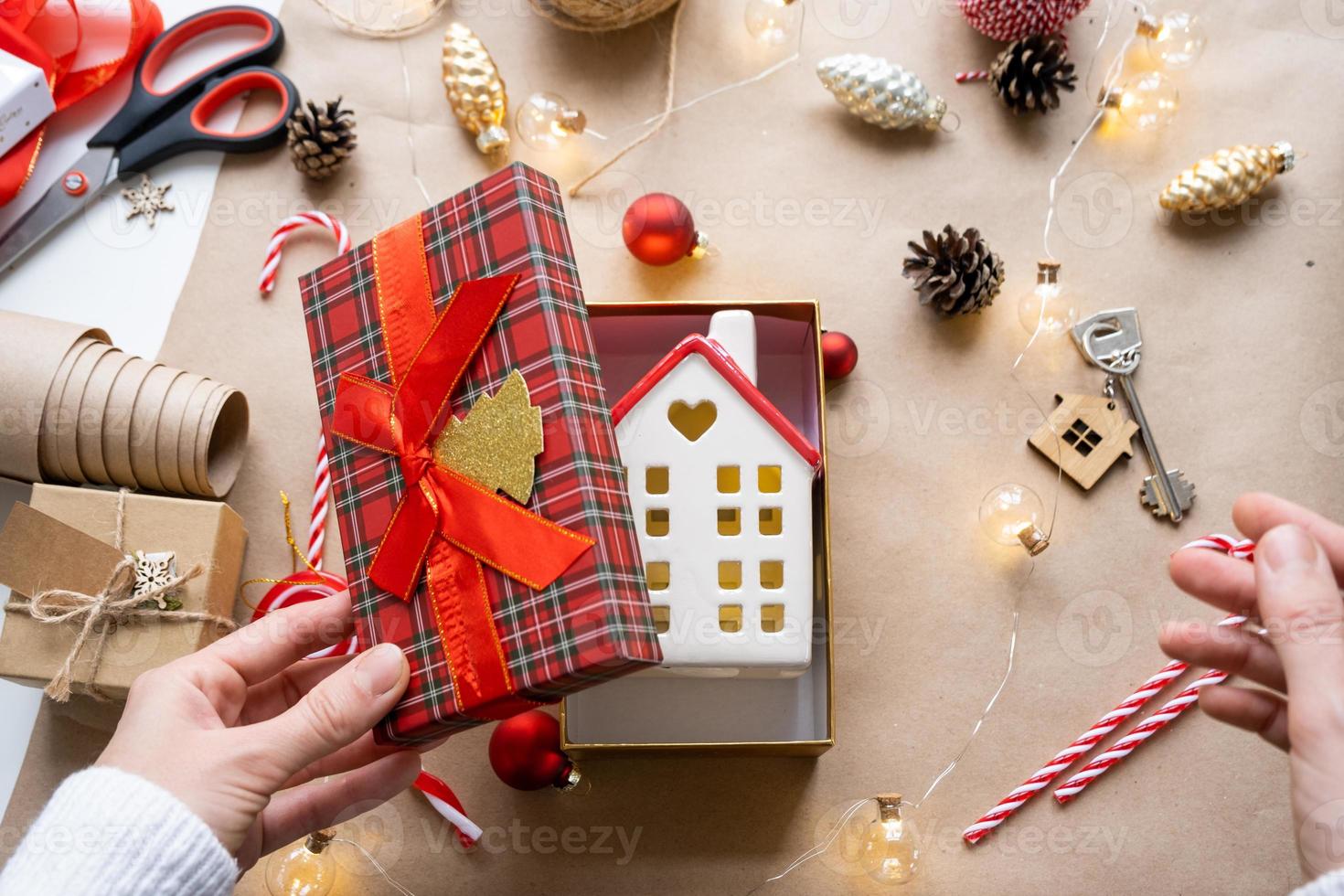 Key to house with keychain on cozy home in gift box with Christmas decor packaging. Pack present for New Year, Christmas. Building, project, moving to new house, mortgage, rent, purchase real estate photo