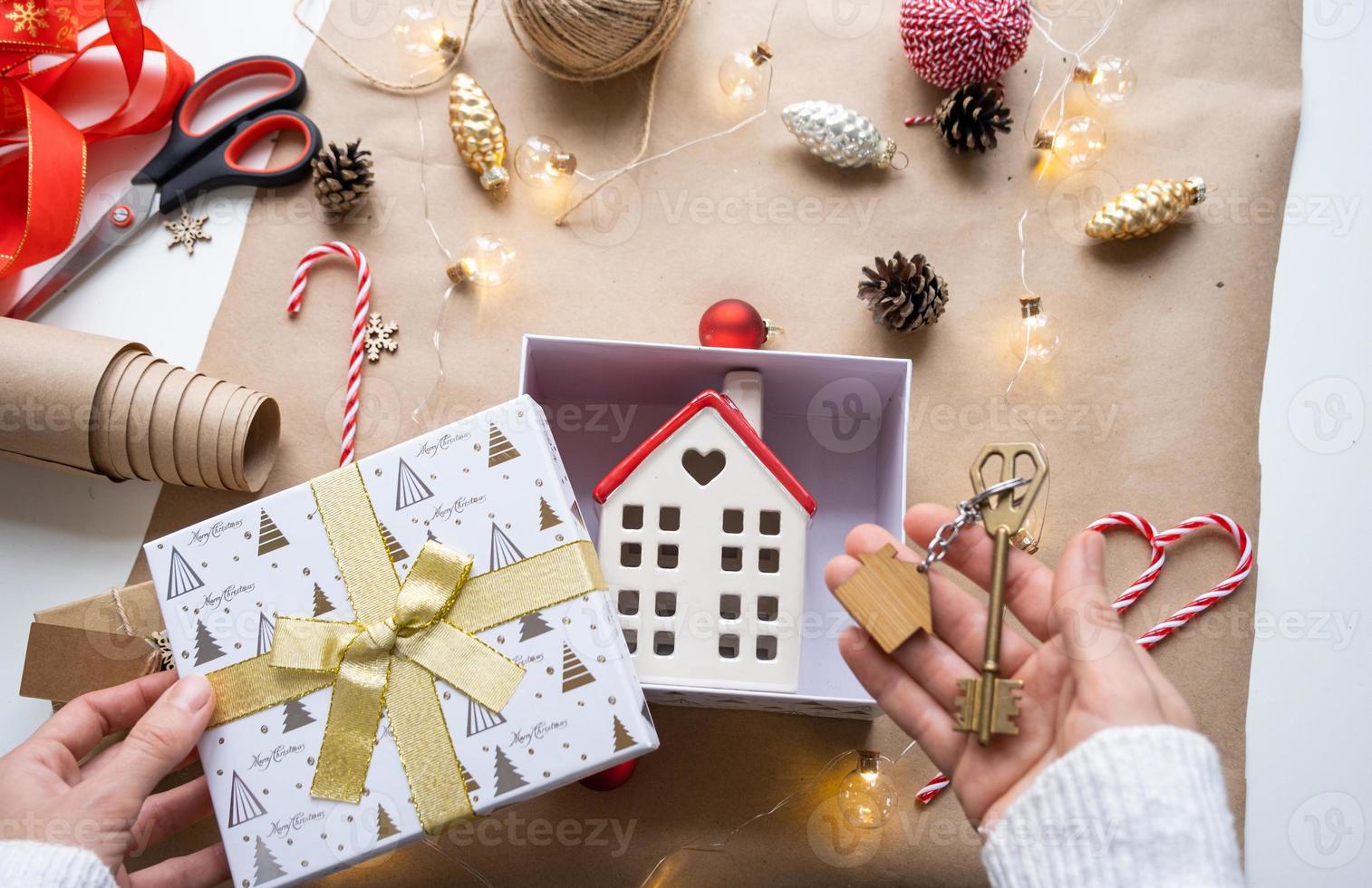 Key to house with keychain on cozy home in gift box with Christmas decor packaging. Pack present for New Year, Christmas. Building, project, moving to new house, mortgage, rent, purchase real estate photo