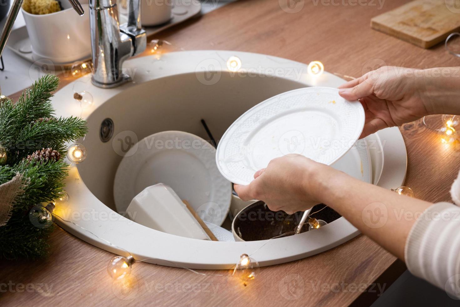 Dirty dishes in the sink in the garlanded kitchen, a holiday after a feast at Christmas. Mess after the guests for the New Year, kitchen cleaning, detergent, cleaning services photo