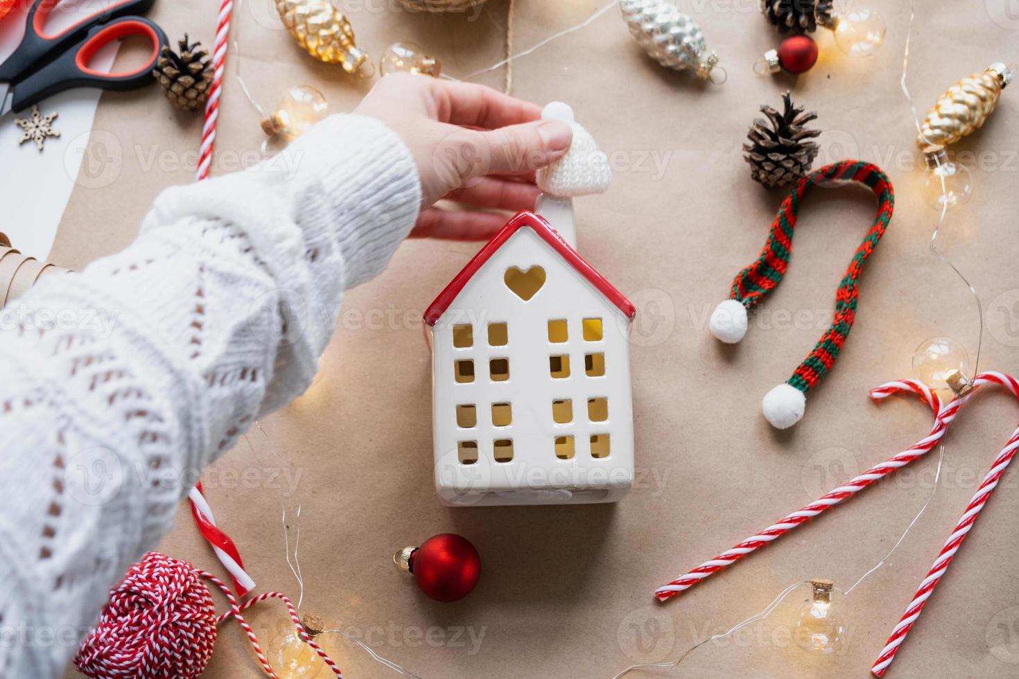 Cozy house in Christmas decor layout, warm knitted scarf, hat, winterization. Winter, snow - home insulation, protection from cold weather, room heating system. Festive mood, Christmas, New Year photo