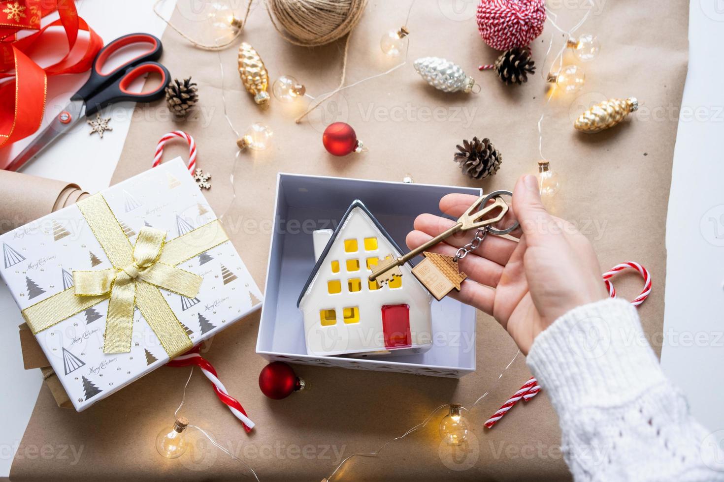 llave de casa con llavero en casa acogedora en caja de regalo con embalaje de decoración navideña. paquete de regalo para año nuevo, navidad. edificio, proyecto, mudanza a casa nueva, hipoteca, alquiler, compra de bienes raíces foto