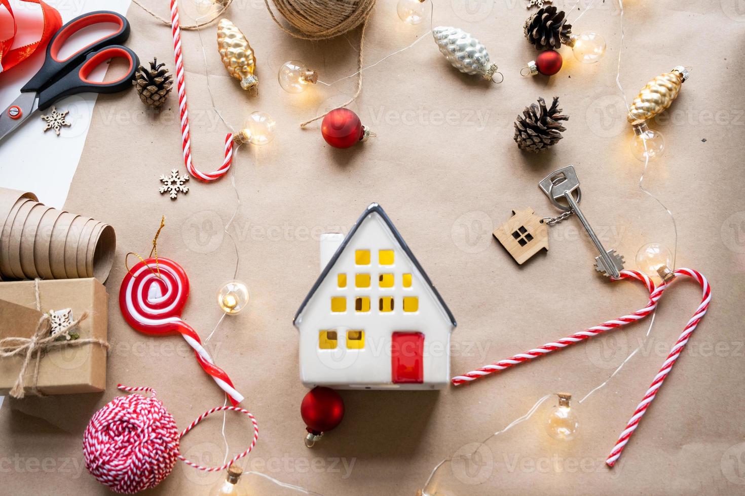 Key to the house with a keychain on a cozy home with a Christmas decor layout. A gift for New Year, Christmas. Building, design, project, moving to new house, mortgage, rent and purchase real estate photo