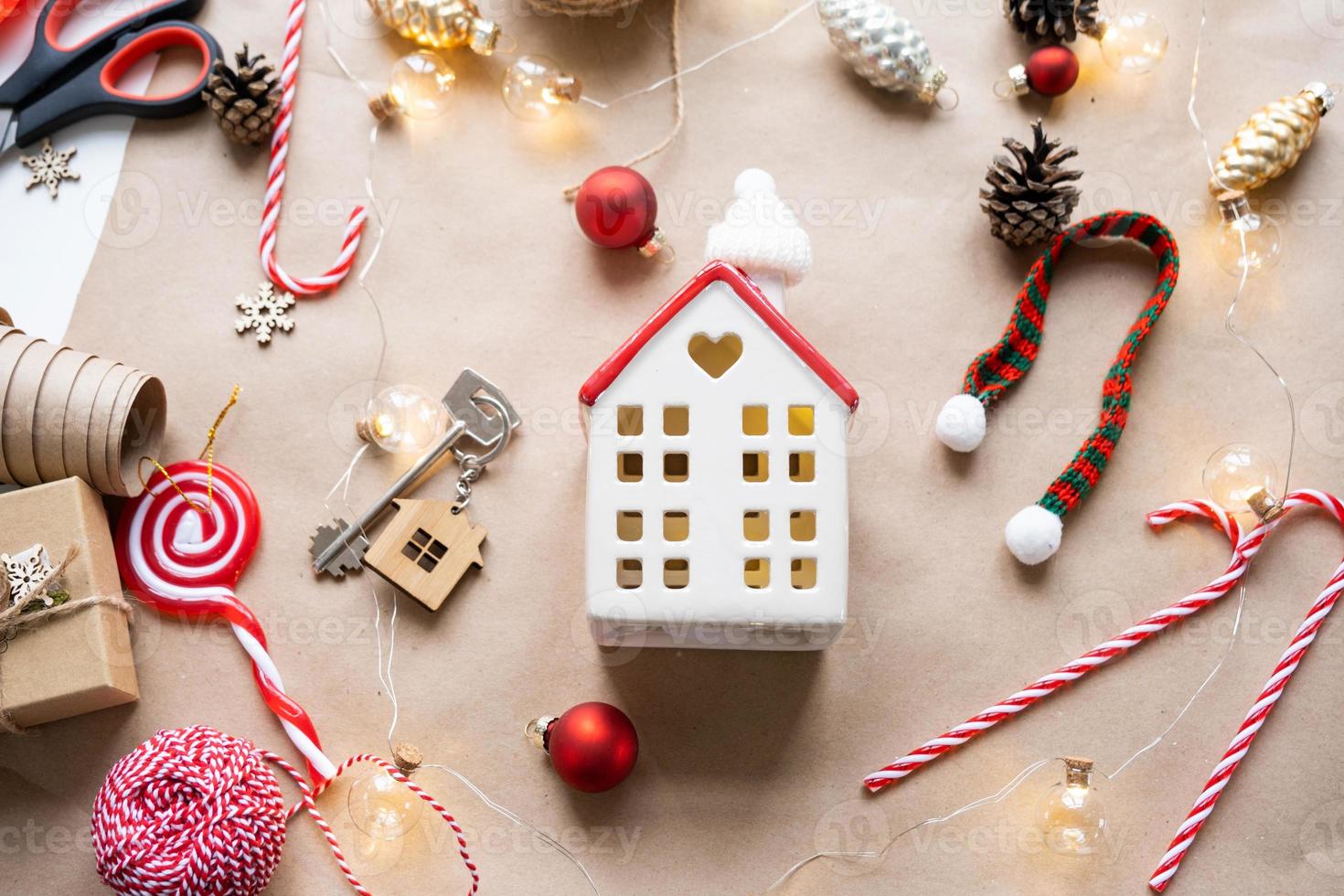 Key to the house with a keychain on a cozy home with a Christmas decor layout. A gift for New Year, Christmas. Building, design, project, moving to new house, mortgage, rent and purchase real estate photo