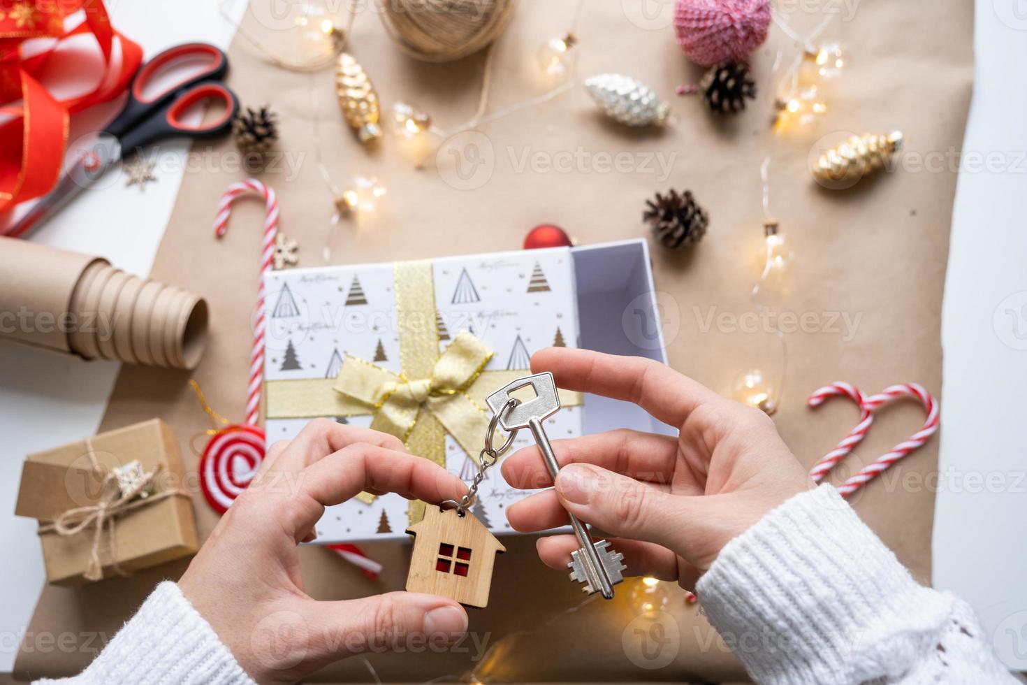 Key to house with keychain on cozy home in gift box with Christmas decor packaging. Pack present for New Year, Christmas. Building, project, moving to new house, mortgage, rent, purchase real estate photo