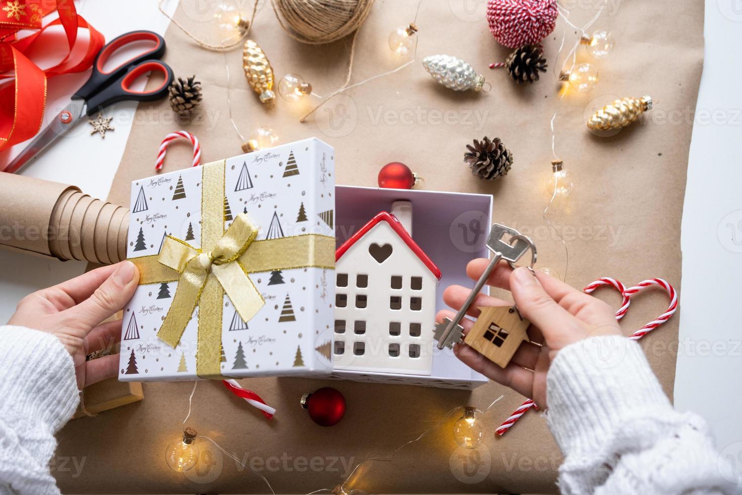 Key to house with keychain on cozy home in gift box with Christmas decor packaging. Pack present for New Year, Christmas. Building, project, moving to new house, mortgage, rent, purchase real estate photo