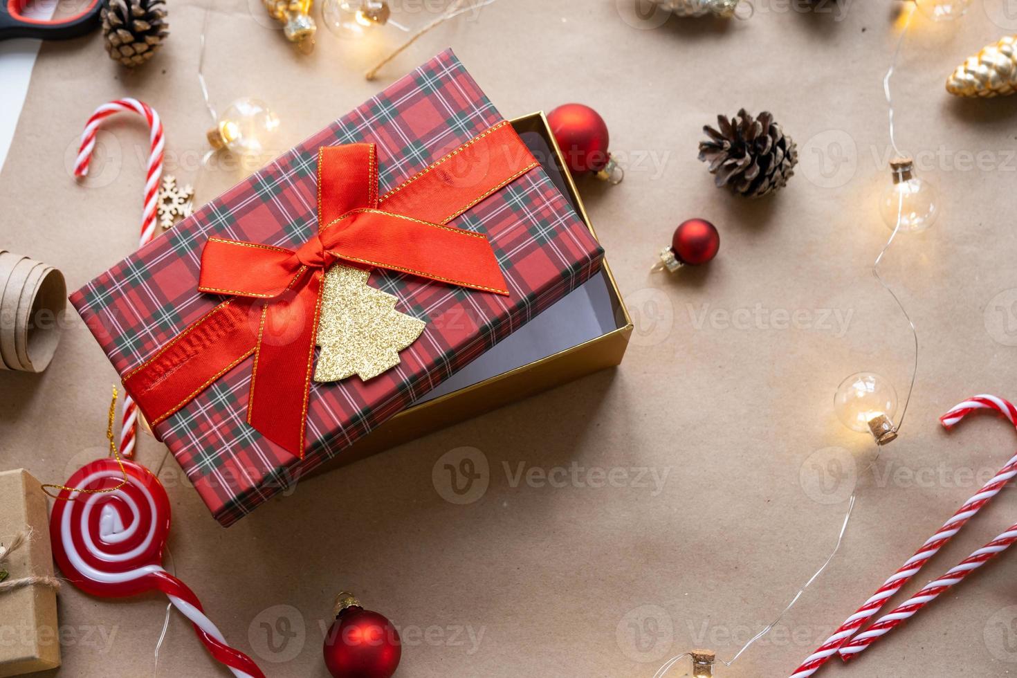 Pack a gift for Christmas and new year in kraft paper, cones, tape, scissors. Tags with mock up, natural decor, hand made, DIY. Festive mood. Flatlay, background photo