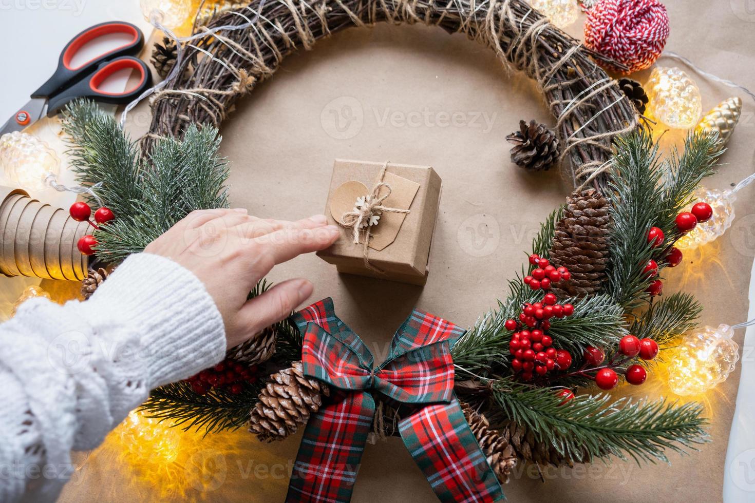 Pack a gift for Christmas and new year in kraft paper, cones, tape, scissors. Tags with mock up, natural decor, hand made, DIY. Festive mood. Flatlay, background photo