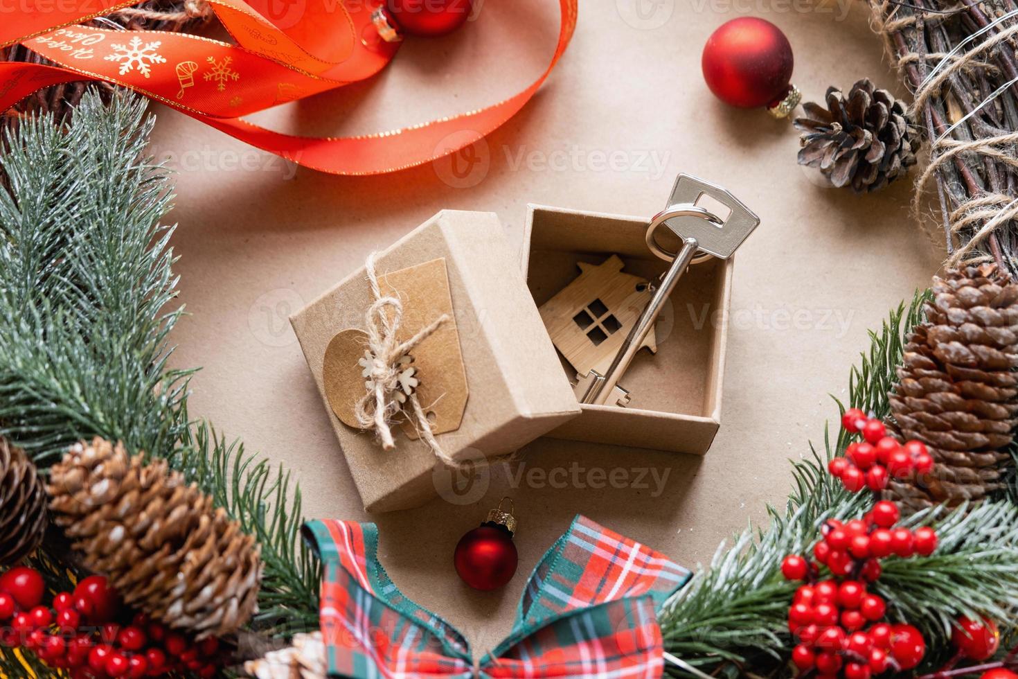 Key to house with keychain on cozy home in gift box with Christmas decor packaging. Pack present for New Year, Christmas. Building, project, moving to new house, mortgage, rent, purchase real estate photo