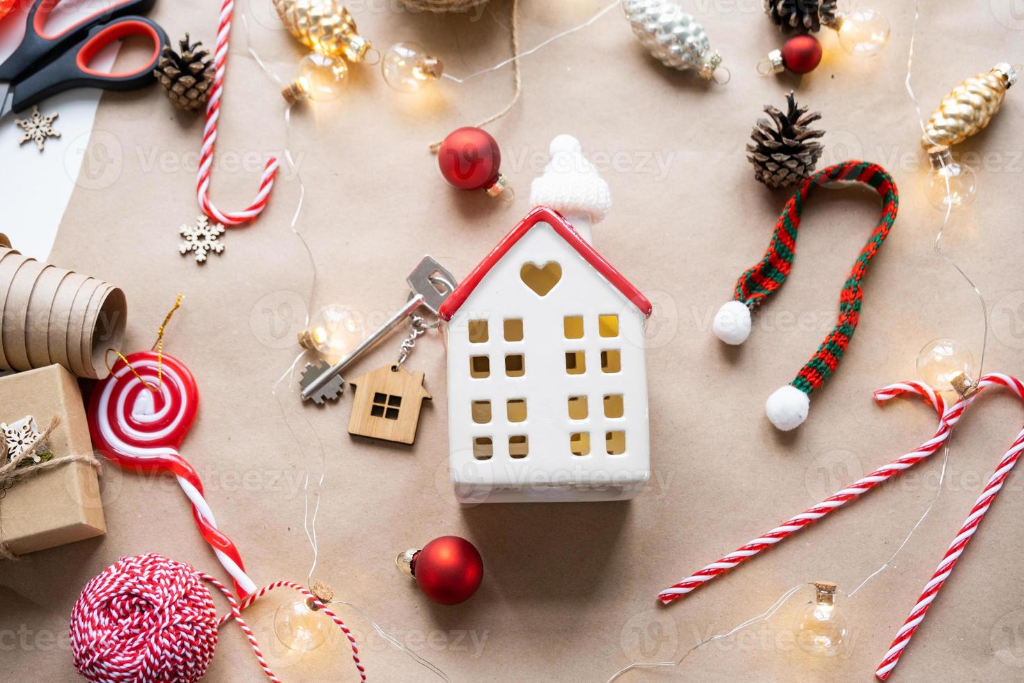 Key to the house with a keychain on a cozy home with a Christmas decor layout. A gift for New Year, Christmas. Building, design, project, moving to new house, mortgage, rent and purchase real estate photo