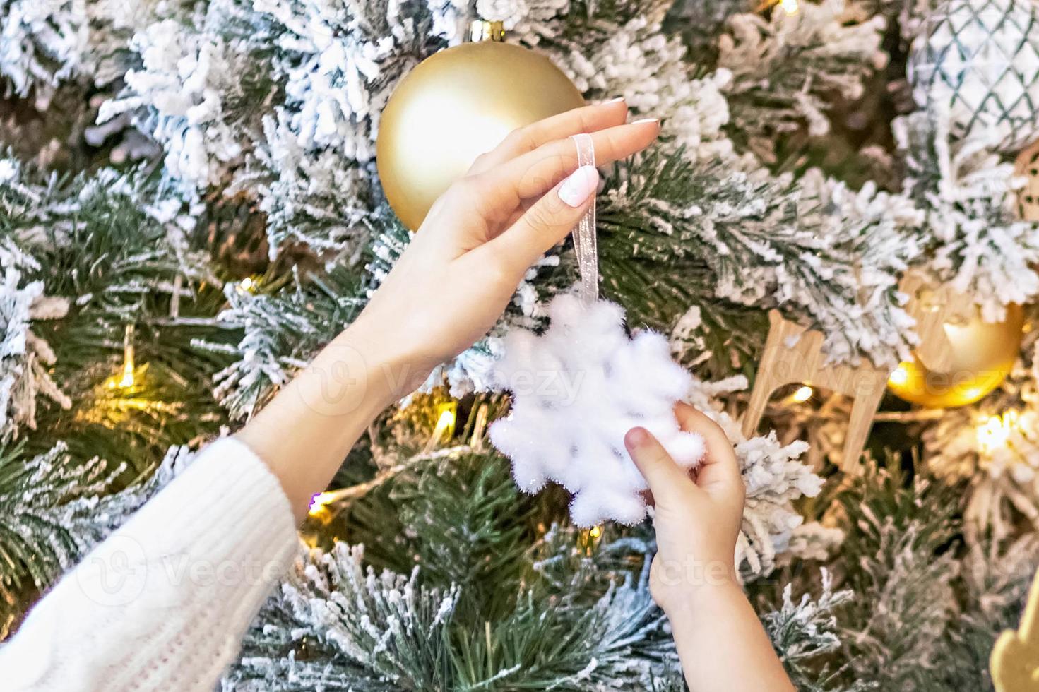 Cute girl toddler and her mom decorate the Christmas tree in the house. Happy family. photo