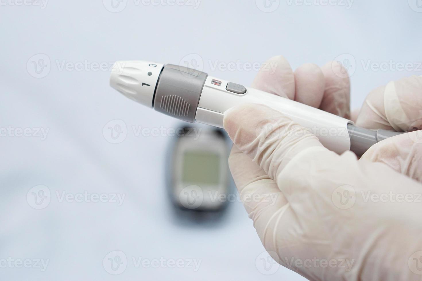 el primer plano de las manos del médico usa guantes que sujetan la jeringa para que la insulina controle el nivel de azúcar en la sangre por glucosa y un lector de sangre está borroso en la parte posterior. foto
