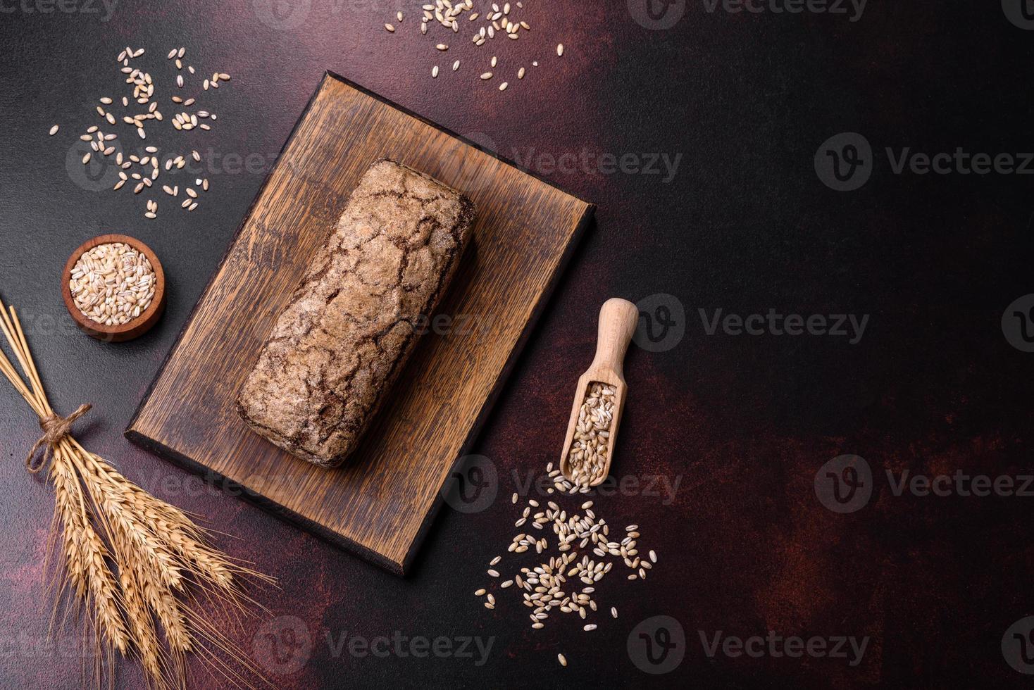 A loaf of brown bread with grains of cereals on a wooden cutting board photo