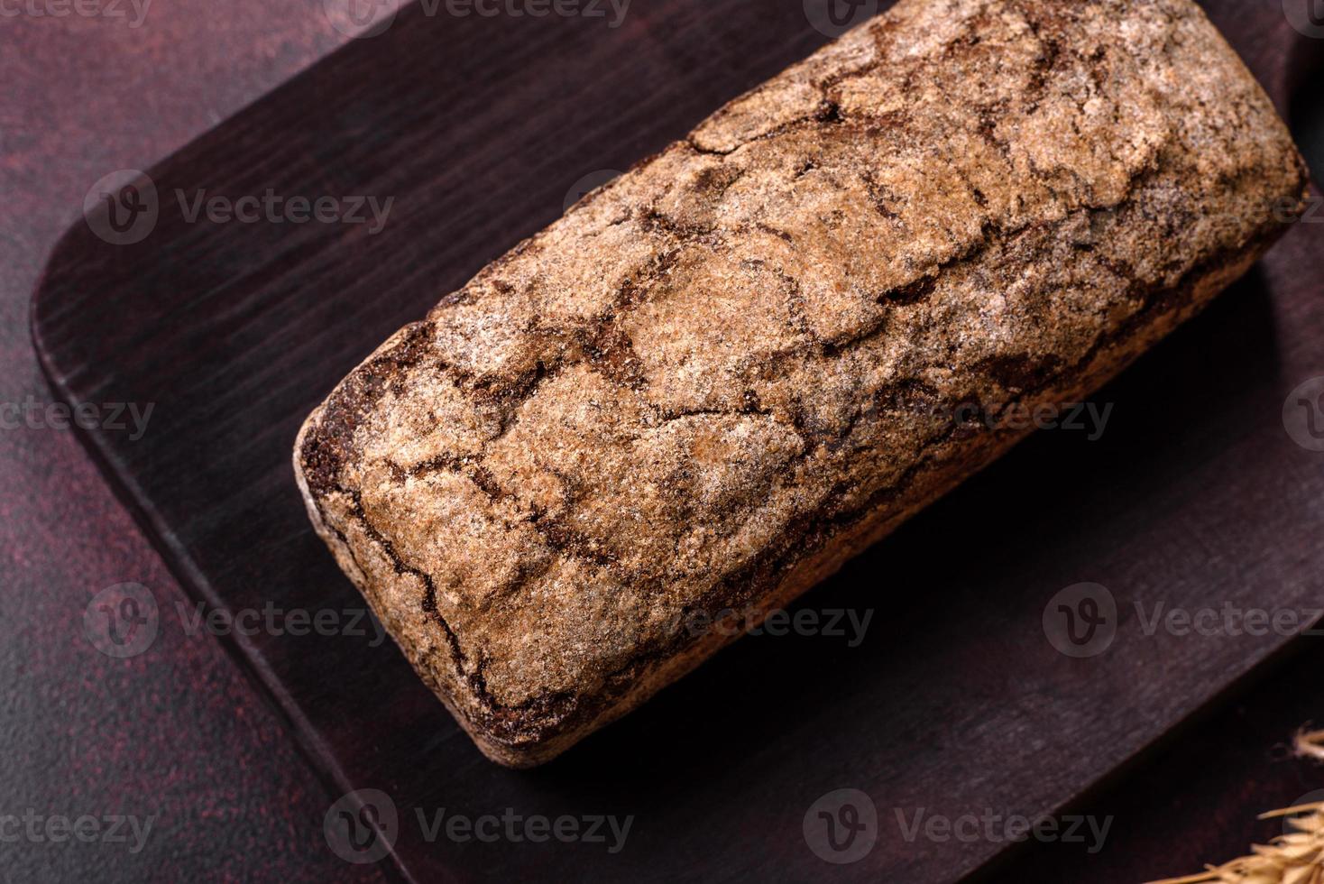 A loaf of brown bread with grains of cereals on a wooden cutting board photo