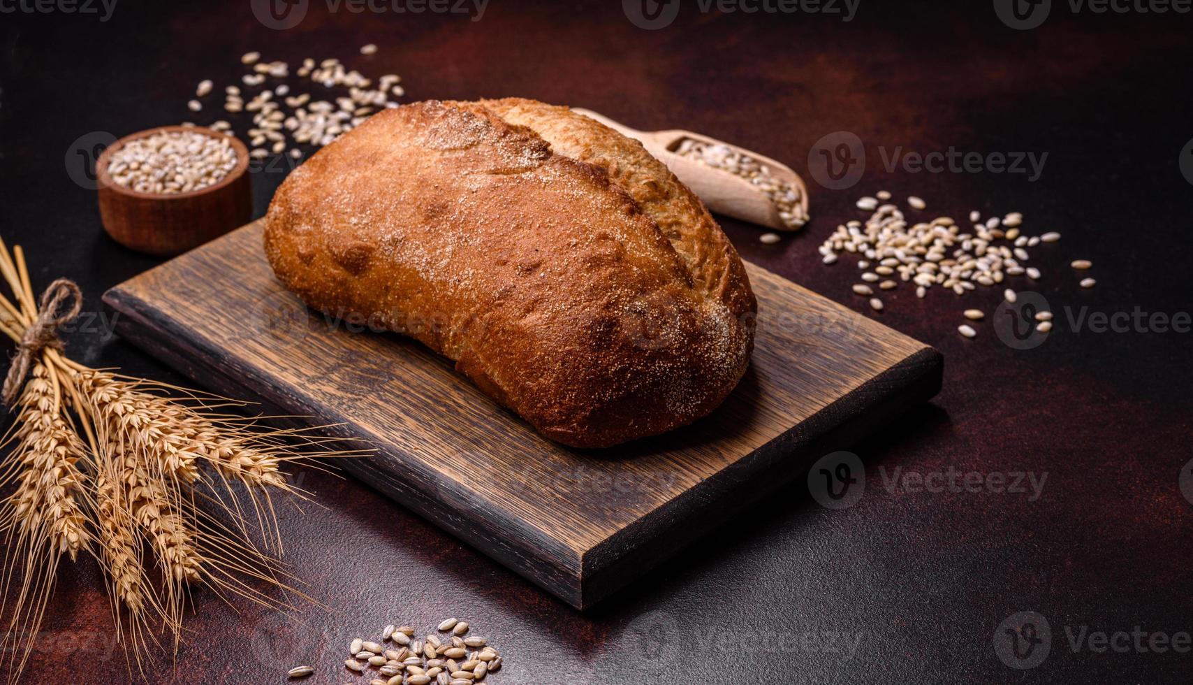 A loaf of brown bread with grains of cereals on a wooden cutting board photo