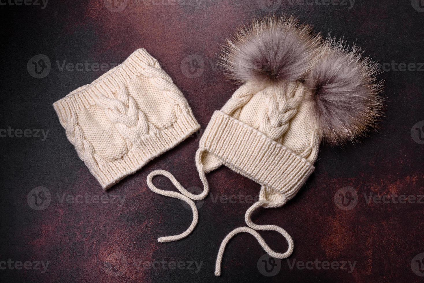 hermoso gorro de invierno de punto blanco con pompones sobre un fondo de hormigón oscuro foto