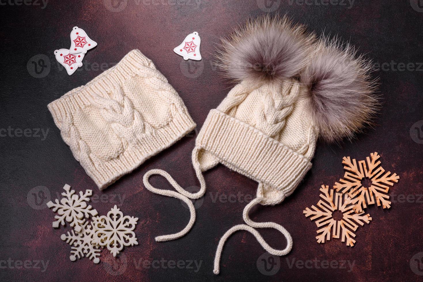 Beautiful white knitted winter cap with pompons on a dark concrete background photo