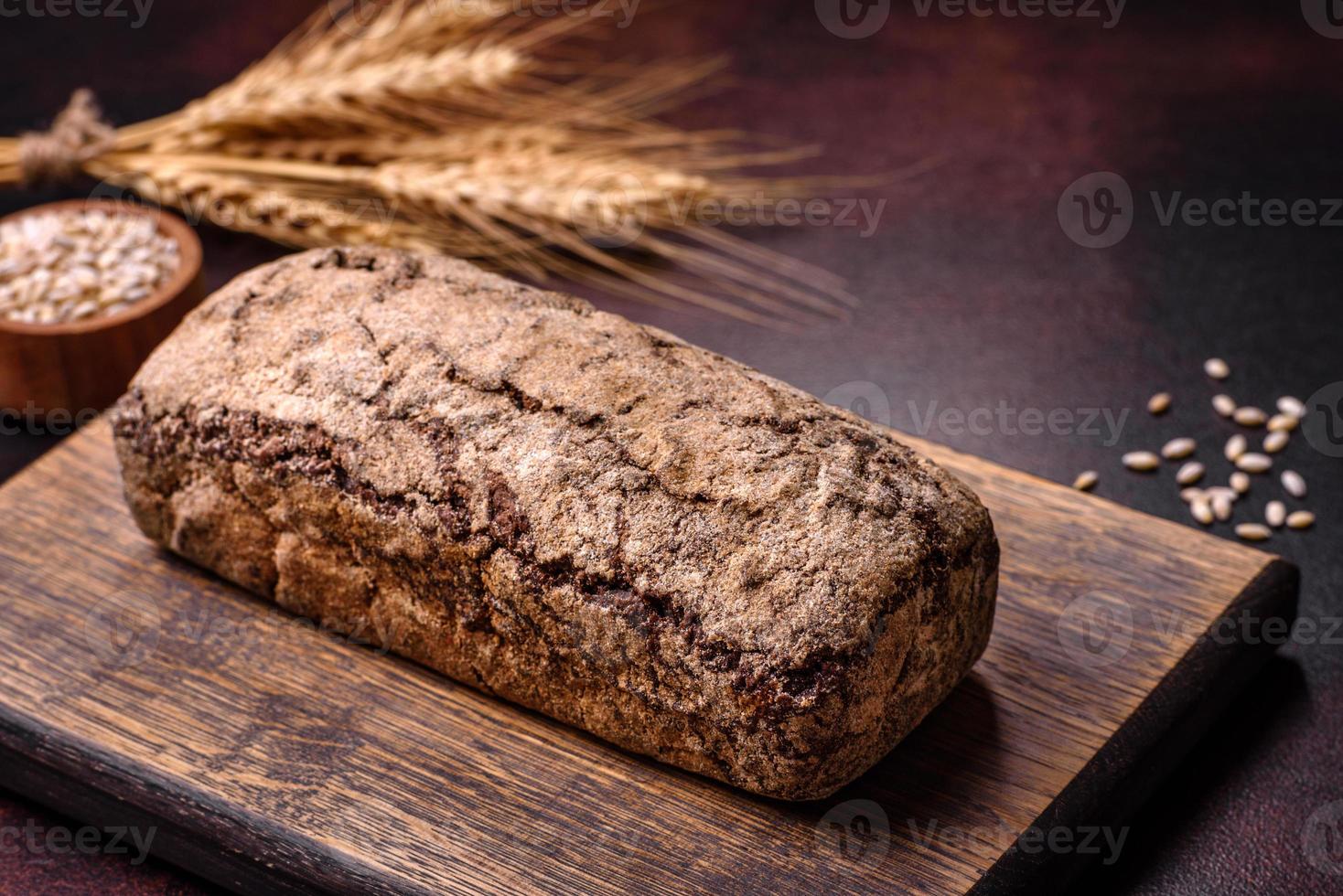 A loaf of brown bread with grains of cereals on a wooden cutting board photo