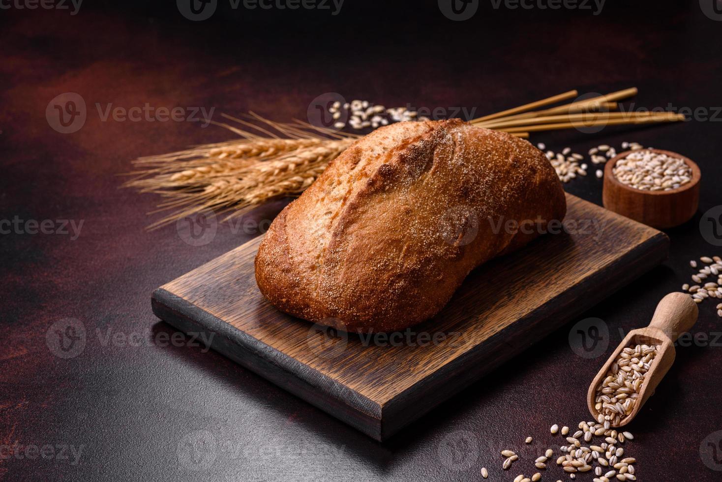 A loaf of brown bread with grains of cereals on a wooden cutting board photo