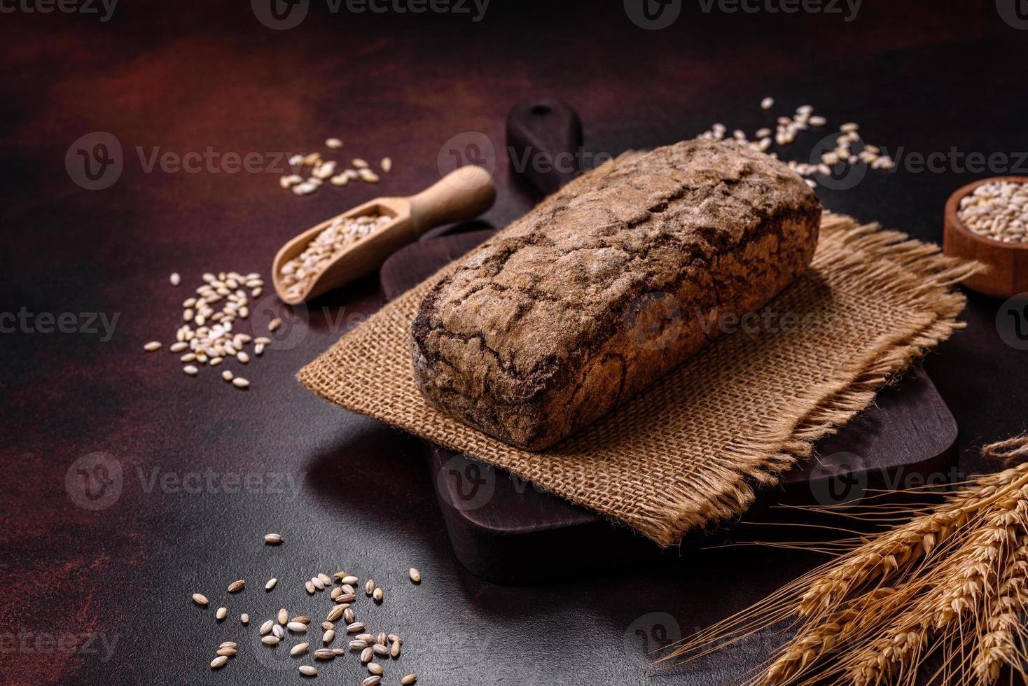 A loaf of brown bread with grains of cereals on a wooden cutting board photo