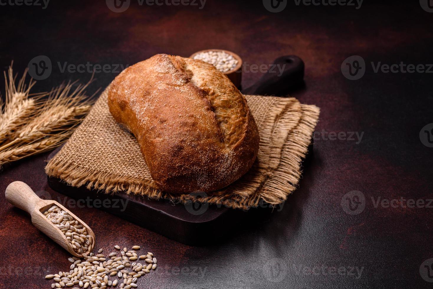 A loaf of brown bread with grains of cereals on a wooden cutting board photo