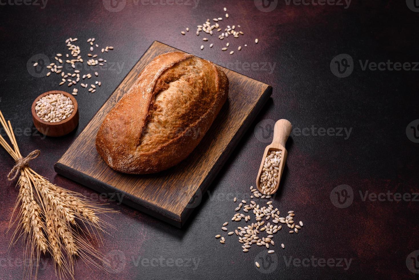 A loaf of brown bread with grains of cereals on a wooden cutting board photo